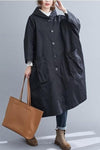 A person wearing the Black One Size Fits All Oversized Water Resistant Windbreaker Jacket by looselyboho, styled with a large brown tote bag, blue jeans, and brown boots. The plain gray background accentuates this chic ensemble that is perfect for any season.